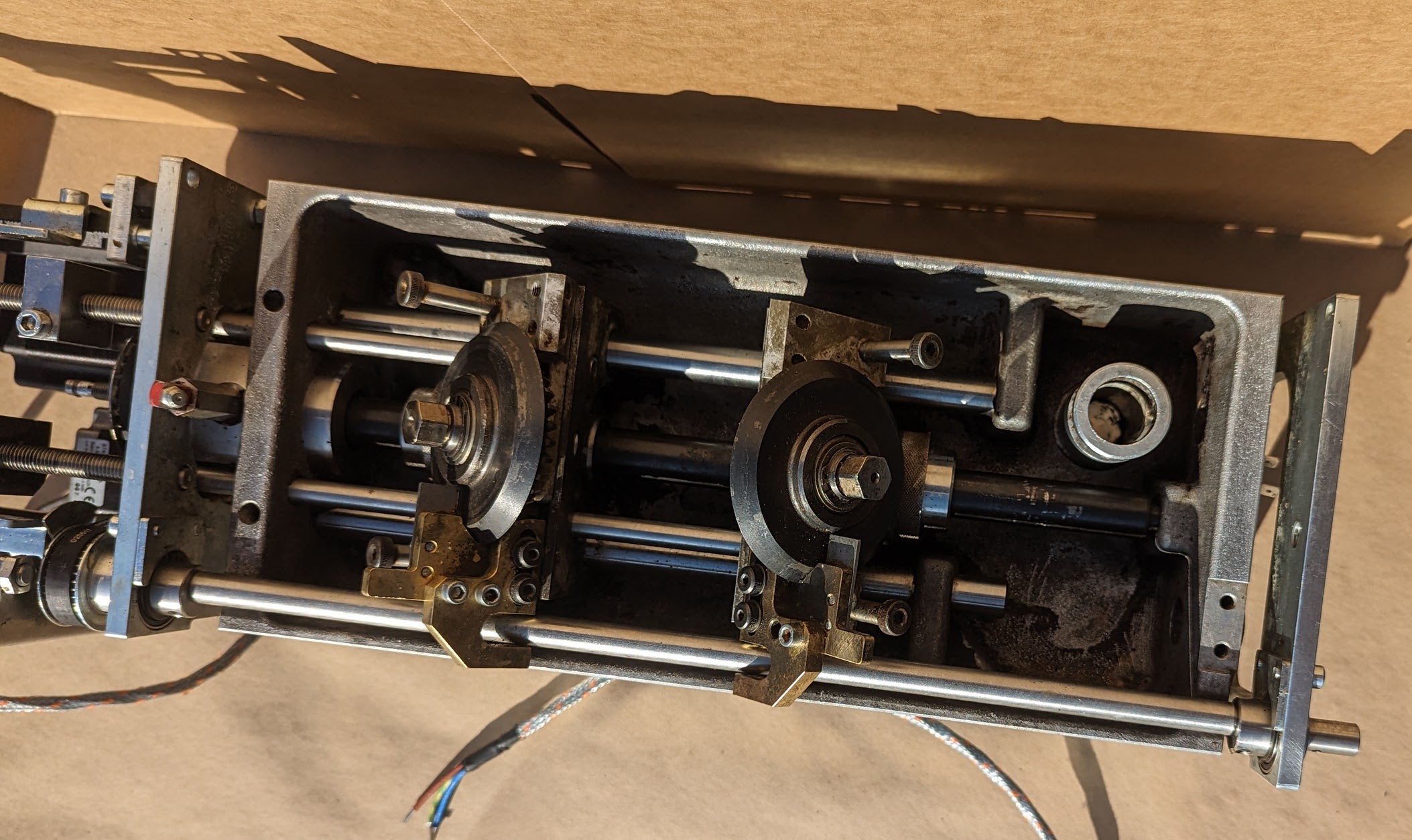 Same applicator mechanism top-down after cleaning — two cam followers and linear guides clean, brass fittings restored