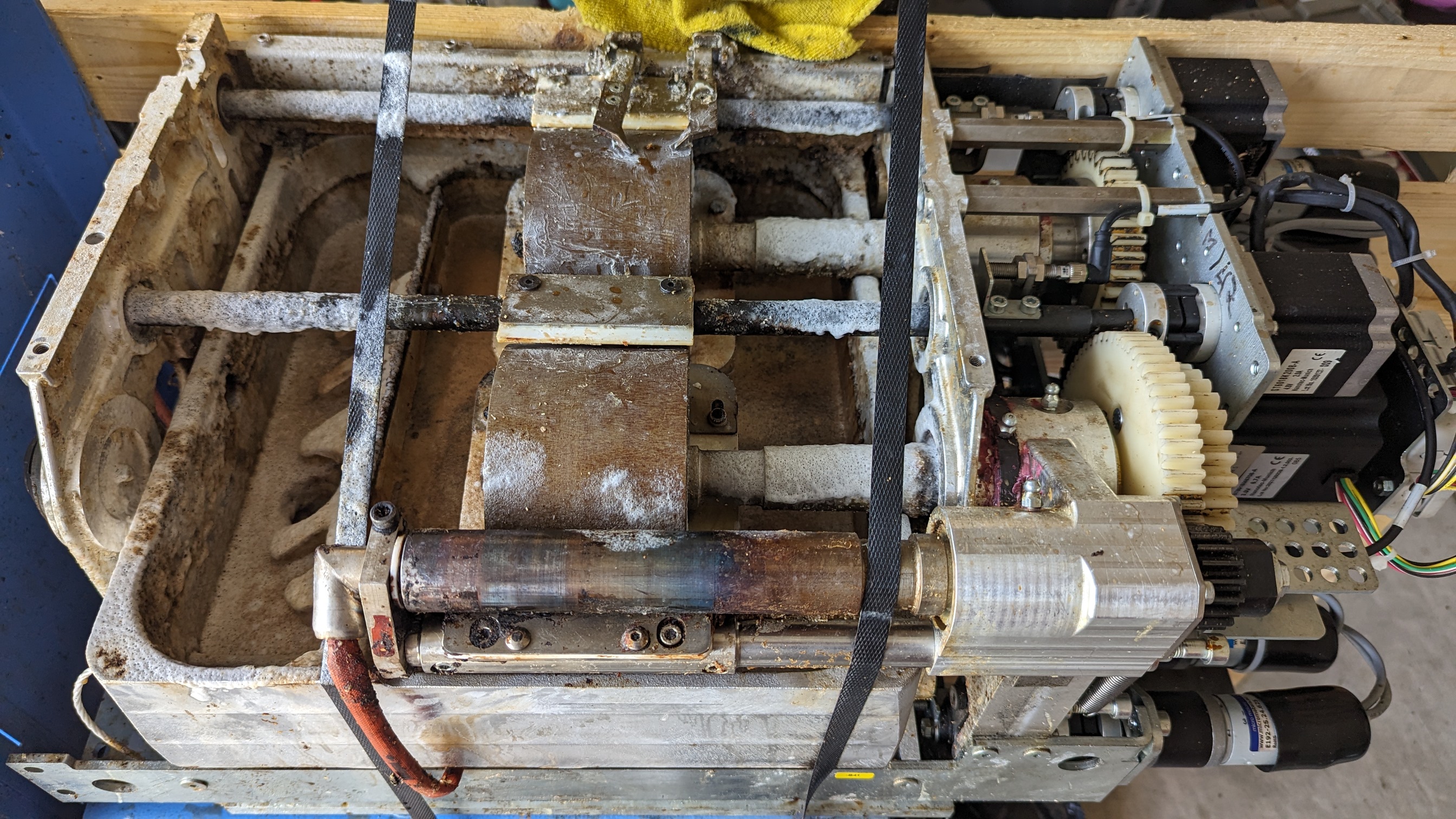 Close-up of glue applicator interior — reservoir completely flooded with polymerized amber adhesive