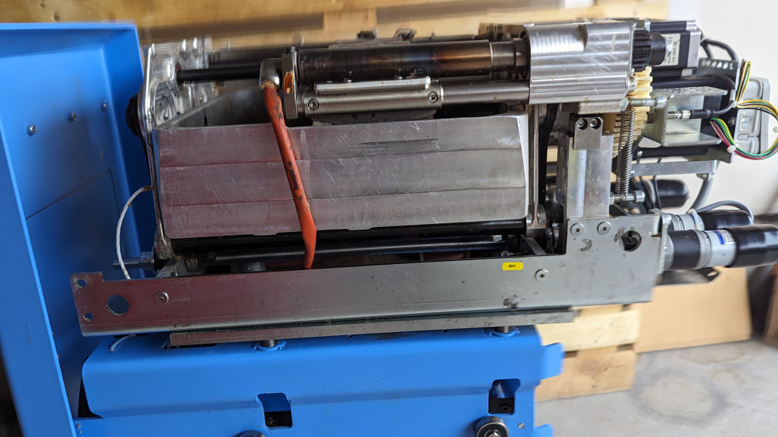 Same applicator unit after cleaning — exterior surfaces clean, gears and drive components restored